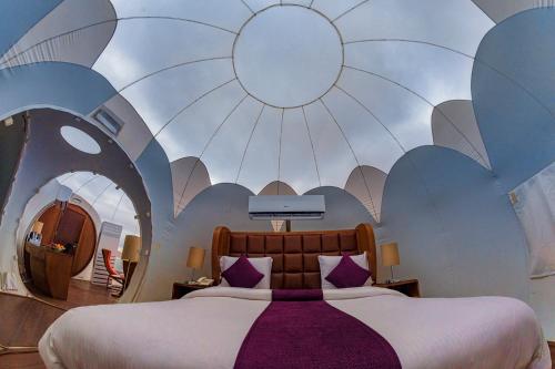 ein Schlafzimmer mit einem großen Bett und einer bemalten Decke in der Unterkunft Petra Bubble Luxotel in Wadi Musa
