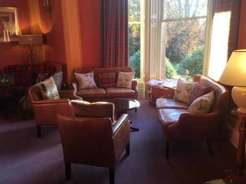 a living room with couches and a large window at Pitlochry Dundarach Hotel in Pitlochry