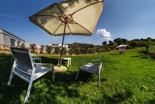two chairs and an umbrella in the grass at Sa Dom'e Malloru in Burcèi