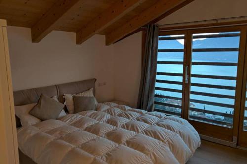 a bedroom with a large bed and a large window at Spectacular views and modern living on Lake Como in Bellano