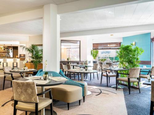 a dining room with tables and chairs at Mercure Maurepas Saint Quentin in Maurepas