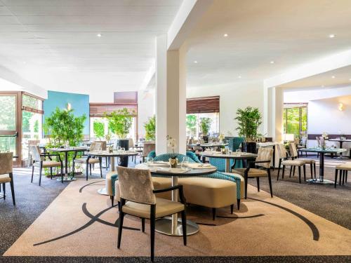 a restaurant with tables and chairs and windows at Mercure Maurepas Saint Quentin in Maurepas