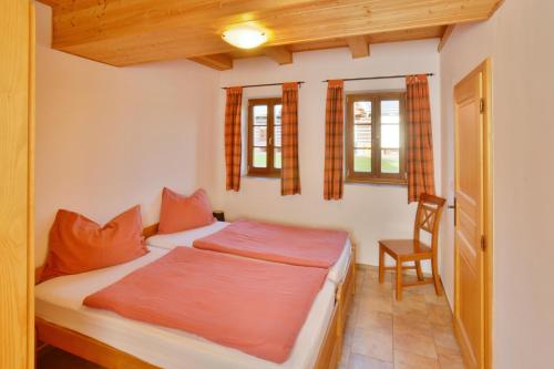 a bedroom with a bed and a chair and two windows at Chalupa Carla in Vrchlabí