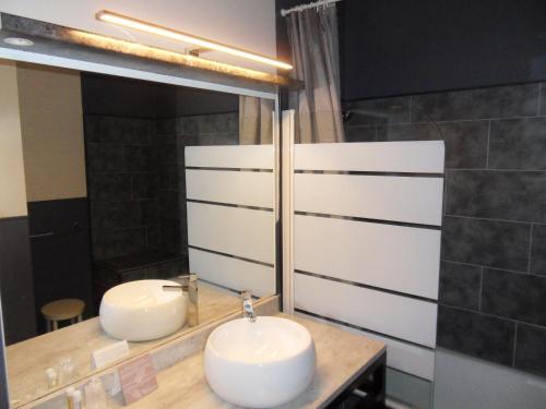 a bathroom with two sinks and a mirror at Logis Hôtel Restaurant Les Aubuns in Caissargues