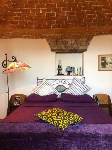 a bed with a purple comforter and a lamp at Bed and breakfast Ca du 5 in Tovo San Giacomo
