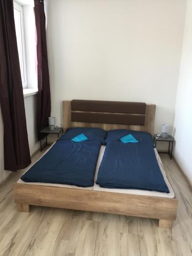 Cama en habitación con 2 almohadas azules en Apartmán č. 2 Haliganda*** en Liptovský Hrádok