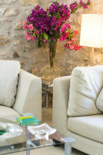 a living room with two couches and a vase with purple flowers at Muazzo Creta Stone House, Nature Escape with Pool, By ThinkVilla in Pigi