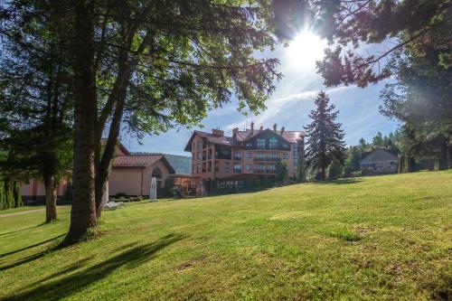 a large house on a grassy hill with trees at СПА-Готель "RESPECT" in Skhidnitsa