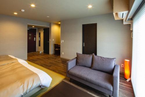 a bedroom with a bed and a couch at Hotel Imari Aioibashi Bettei in Imari
