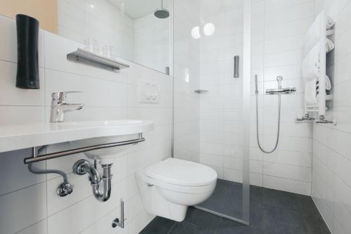 a white bathroom with a toilet and a shower at Reykjavik Lights Hotel by Keahotels in Reykjavík