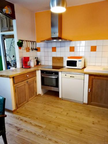 - une cuisine avec des placards en bois et un four micro-ondes blanc dans l'établissement L'usine, à Pont-de-Labeaume