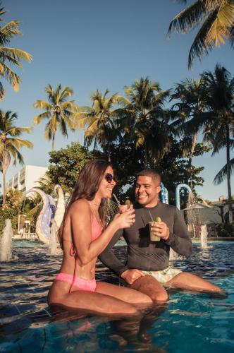 a man and woman sitting in the water with drinks at Matsubara Acqua Park Hotel in Maceió