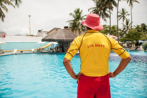 a man in a yellow shirt and a red hat by a swimming pool at Matsubara Acqua Park Hotel in Maceió