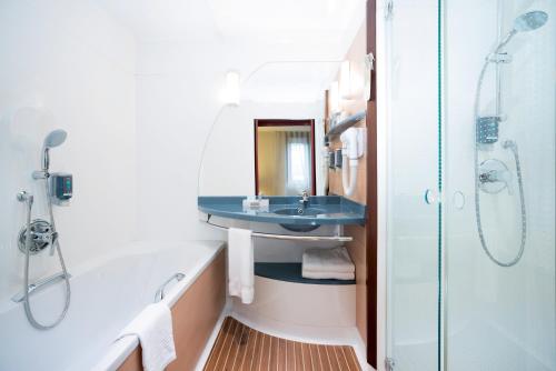 uma casa de banho com um lavatório, uma banheira e um chuveiro em Novotel Marrakech Hivernage em Marraquexe