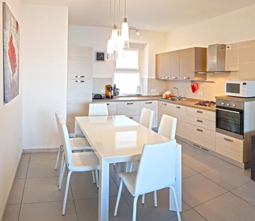 a kitchen with a white table and white chairs at Villetta Sogno sul Lago by Gardadomusmea in Tremosine Sul Garda