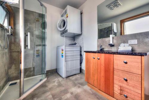 a bathroom with a shower and a sink and a refrigerator at Freycinet Stone Studio 7 - Quartz in Coles Bay
