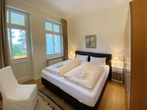 a bedroom with a large white bed and a chair at Villa Caprivi - Ferienwohnung 3 in Heringsdorf
