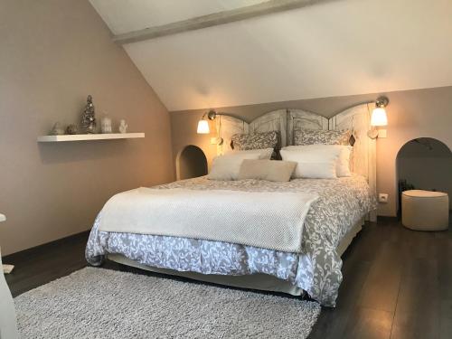 una camera da letto con un grande letto con lenzuola e cuscini bianchi di Chambres d'Hôtes des Demoiselles a Ville-Saint-Jacques