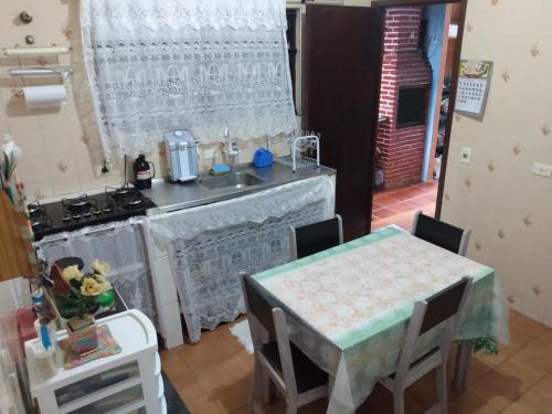 une cuisine avec une table, un évier et une cuisinière dans l'établissement Casa Próximo Centro Itanhaém, à Itanhaém