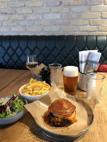 a table with a sandwich and french fries and a glass of beer at ibis Saint-Omer Centre in Saint-Omer