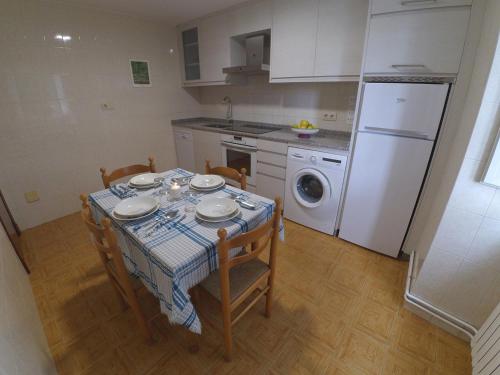 a kitchen with a table with chairs and a washing machine at Holiday Home El Olivo in Puentedeume