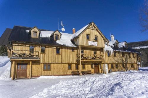 a large wooden building with snow on it at Apartmány Penzion Koula in Pec pod Sněžkou