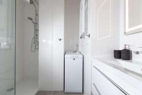 een witte badkamer met een douche en een koelkast bij Resort Apartamenty Klifowa Rewal 29 in Rewal