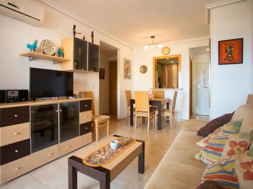 sala de estar con sofá, TV y mesa en Apartment Jardines del Mar - Azahar by Interhome, en El Borseral