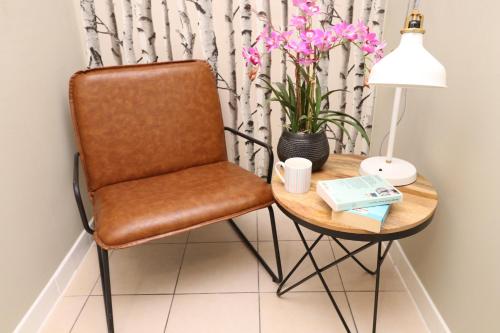 a chair and a table with a lamp and flowers at The Spinney in Bracknell