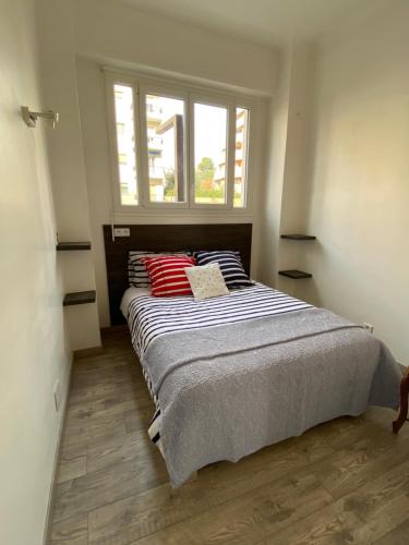 une chambre avec un lit avec des oreillers rouges et une fenêtre dans l'établissement PALAIS ELISABETH PROMENADE DES ANGLAIS, à Nice