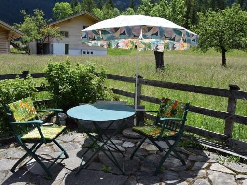 OberriedにあるApartment Kronegg # 2 by Interhomeの柵の横にテーブルと椅子2脚と傘