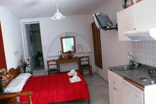 Habitación con cama roja en una cocina con fregadero en Mike's Studios, en Naxos Chora
