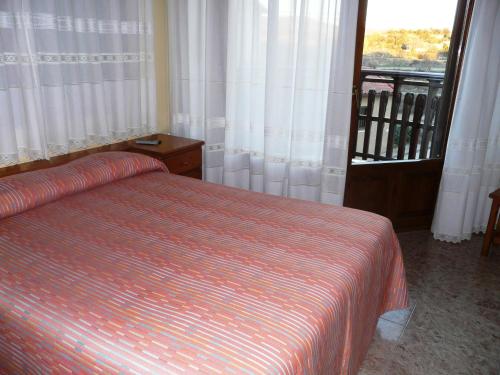 a bedroom with a bed with a striped bedspread and a window at Hostal Rural Casa Castro in Alberuela de la Liena