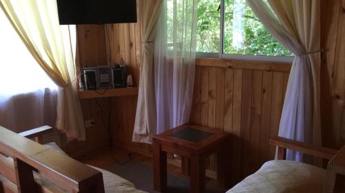 Dormitorio con ventana, cama y mesa en Cabañas Trabunco en Pucón
