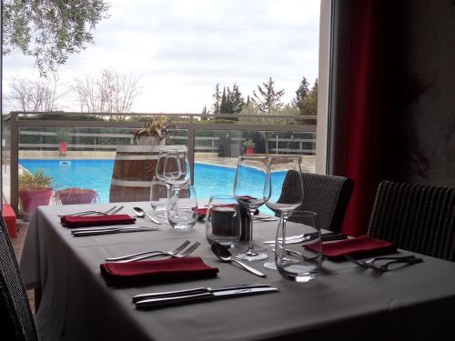 a table with red napkins and wine glasses on it at Logis Hôtel Restaurant Les Aubuns in Caissargues