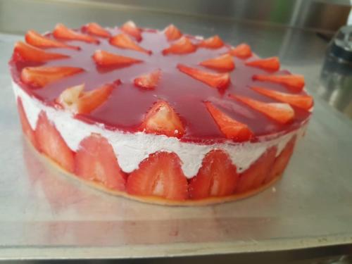 a cake with strawberries on top on a table at Logis Hôtel Restaurant Les Aubuns in Caissargues