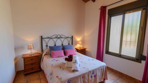 um quarto com uma cama com almofadas cor-de-rosa e azuis em Casa Rural El Moral em Málaga
