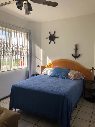 a bedroom with a blue bed and a window at Lindo apartamento super completo em Meia Praia, 100 metros do mar e 10 quadras do centro in Itapema