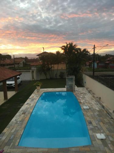 una piscina blu con tramonto sullo sfondo di Itanhaém Maravilhosa, Bilhar, Sky, WiFi, Piscina e churrasqueira grande, Gramado, Casa linda de alto padrão a 600m praia a Itanhaém