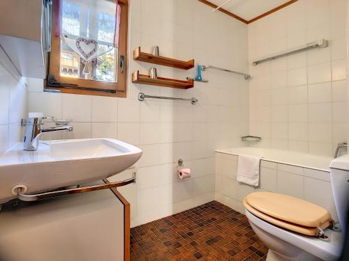 ein Bad mit einem Waschbecken, einem WC und einem Fenster in der Unterkunft Apartment Summit Combles in Verbier