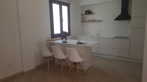 una cocina con encimeras y taburetes blancos y una ventana en Apartamento Palacio Azcárate Marisa Sanchez, en Ezcaray
