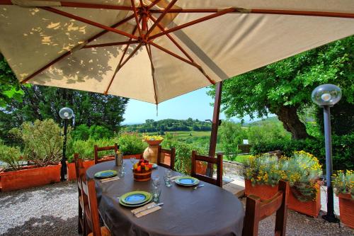 a table with an umbrella on a patio at Villa Uccellaia by PosarelliVillas in Agello