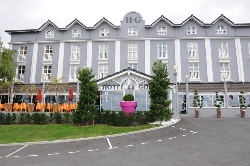 ein großes weißes Gebäude mit einem Blumentopf auf einem Parkplatz in der Unterkunft Hotel Du Golf in Saint-Étienne