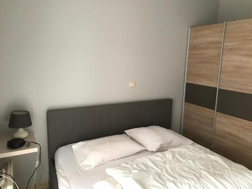 a bed with white sheets and a wooden headboard at Appartement Koksijde in Koksijde