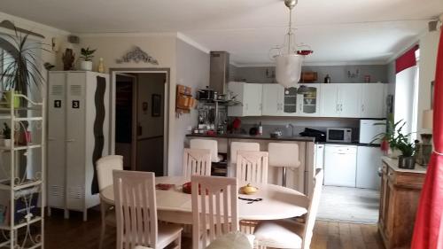 cocina con armarios blancos, mesa y sillas en Appartement La Loob Gites de Daumesnil étage en Morlaix