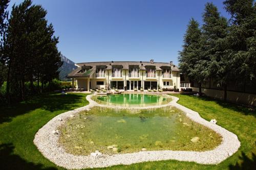 a large house with a pond in the yard at Momentum Hotel in Anif