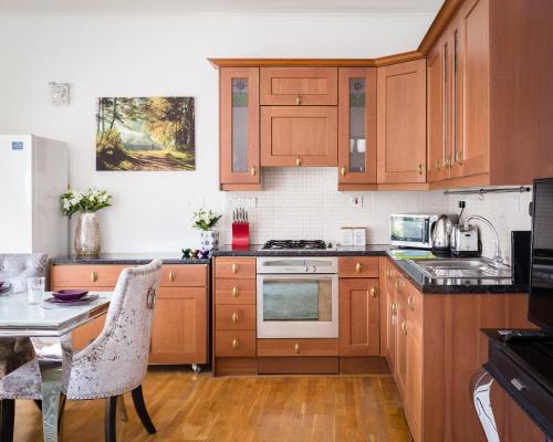 - une cuisine avec des placards en bois, une table et des chaises dans l'établissement PickThePlace Apartment behind Selfridges, à Londres
