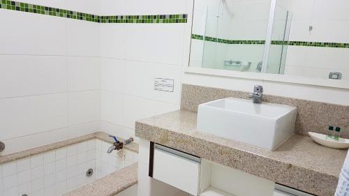 a white bathroom with a sink and a mirror at Hotel Termas Gravatal in Gravatal