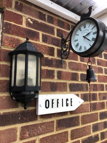 a clock and an office sign on a brick wall at Hogwarts Bed and Continental Breakfast in Sheerness