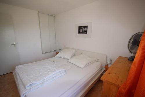 - une chambre avec un lit blanc et une table en bois dans l'établissement Belle villa 2 chambres terrasse vue réserve naturelle dans résidence sécurisée avec piscine commune 800m de la mer LRCS50, à Portiragnes